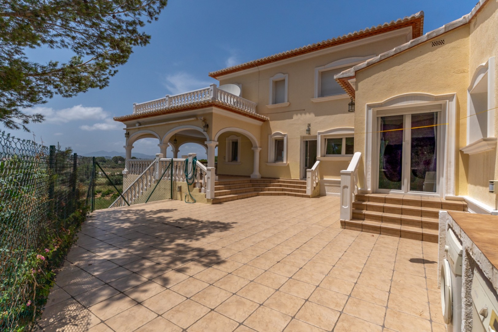 Spacious tiled terrace featuring an arched naya with white balustrades. The area includes an outdoor laundry space and offers open views of the surrounding countryside.