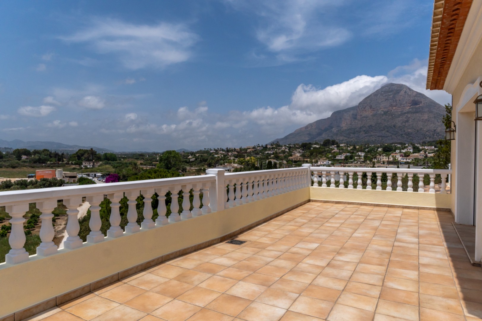 Upper terrace featuring terracotta-toned tiling and a classic white balustrade, providing panoramic views of the Montgó mountain and surrounding valley.