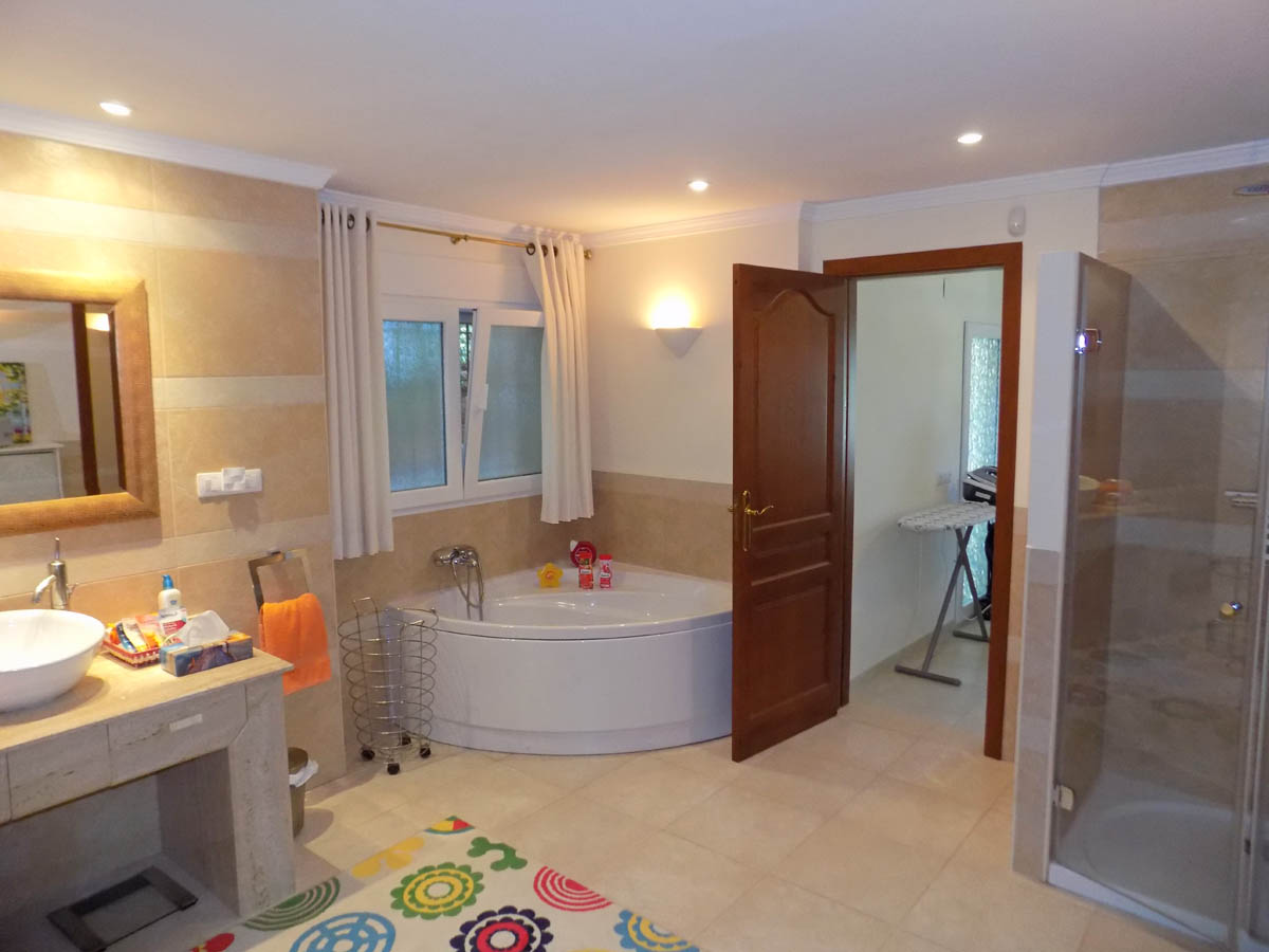 Bathroom featuring a corner jacuzzi tub, a separate walk-in shower with glass enclosure, and a stone vanity with a vessel sink and recessed lighting.