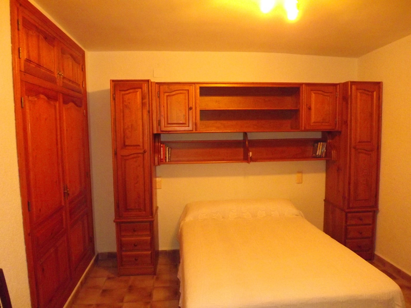 Bedroom featuring solid wood furniture, including a built-in wardrobe and a bridge unit with shelving and drawers surrounding the bed.