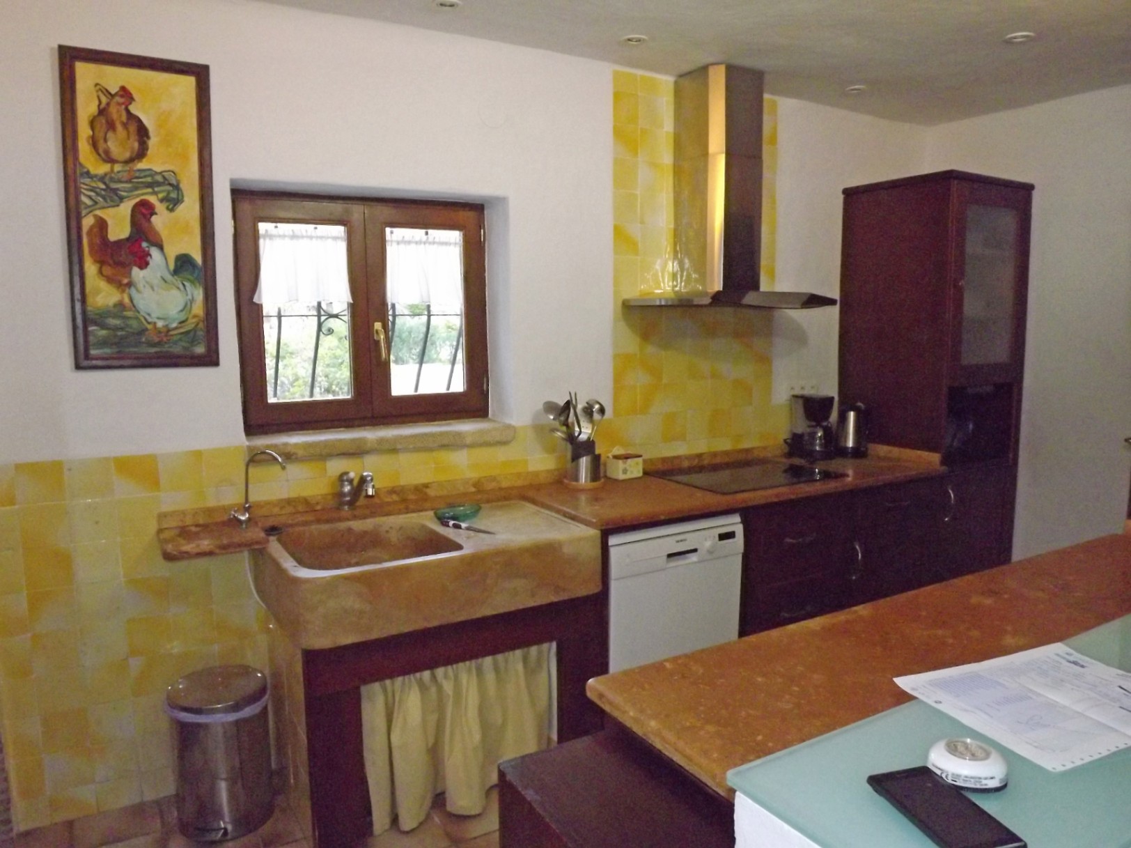Rustic style kitchen featuring a large natural stone sink, yellow tiled backsplash, dark wood cabinetry, and marble countertops with recessed ceiling lighting.