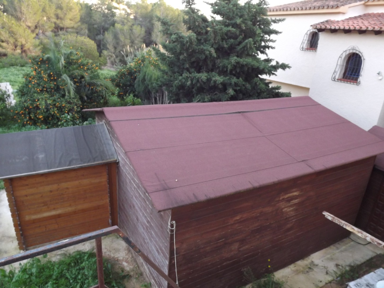Wooden storage sheds situated on the expansive plot, nestled among Mediterranean fruit trees and natural greenery near the villa.