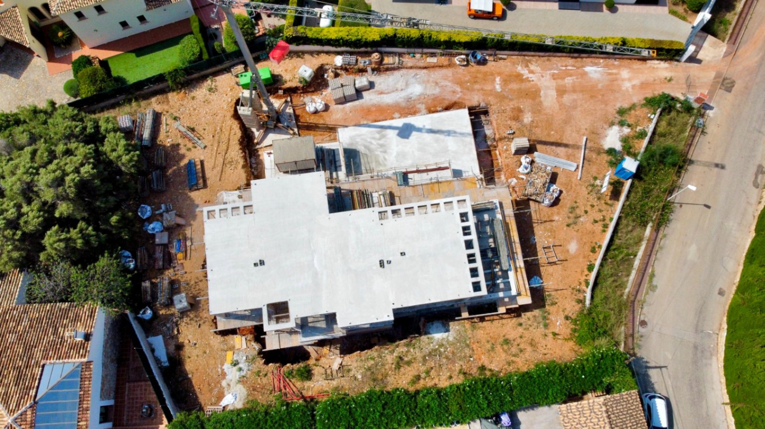 Aerial view of the construction progress on the flat plot, showing the reinforced concrete structure and crane at the Garroferal del Montgó site.