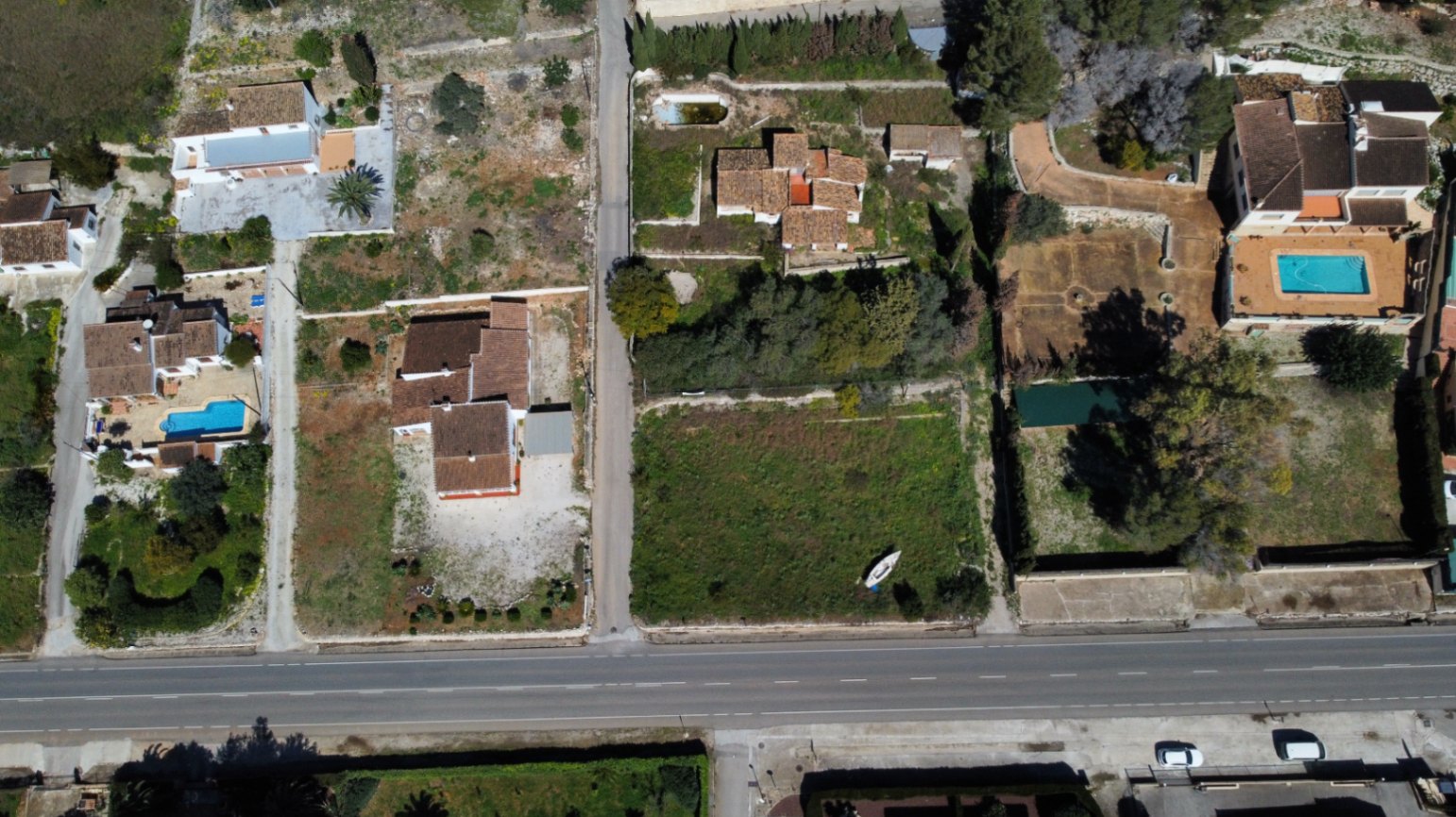 Aerial view of the 2,895sqm plot in Jávea, showcasing the existing house, the vast expandable land area, and the convenient access from the main road.