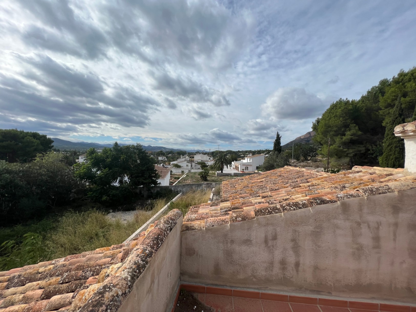 Elevated views from the upper terrace across the Montgó valley, showcasing traditional terracotta roofing and the lush Mediterranean surroundings of Jávea.