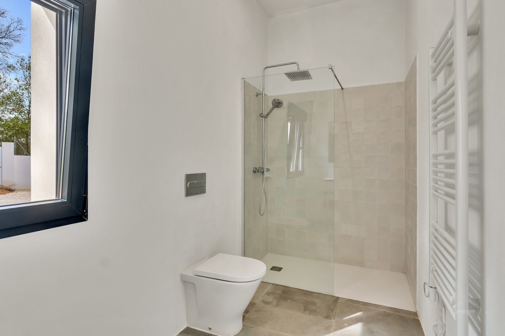 Modern bathroom featuring a walk-in shower with glass partition, rain shower head, wall-mounted toilet, and a white heated towel rail against minimalist walls.