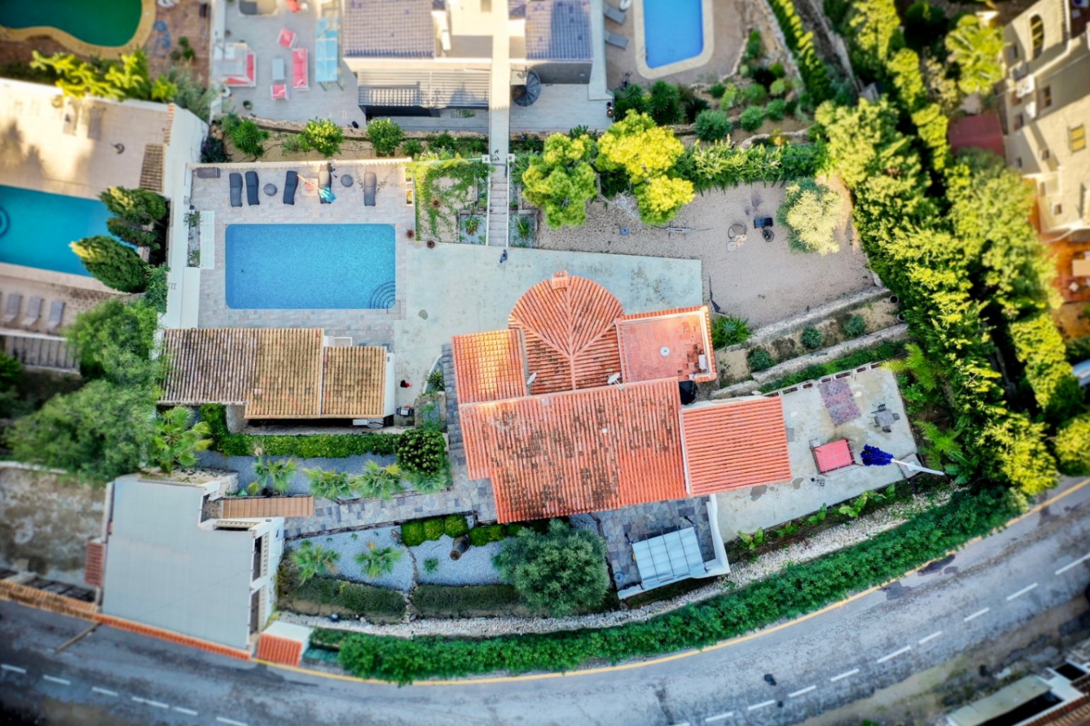 Aerial view of the villa showcasing the plot layout, rectangular swimming pool with stone terrace, and traditional terracotta tile roofing.