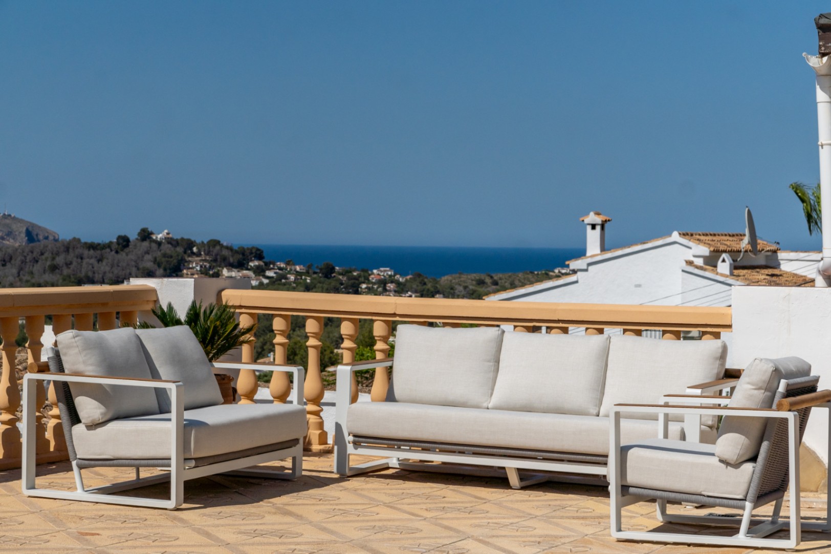 Elevated terrace featuring modern outdoor lounge furniture and panoramic views of the Mediterranean Sea and the coastal landscape of Jávea.