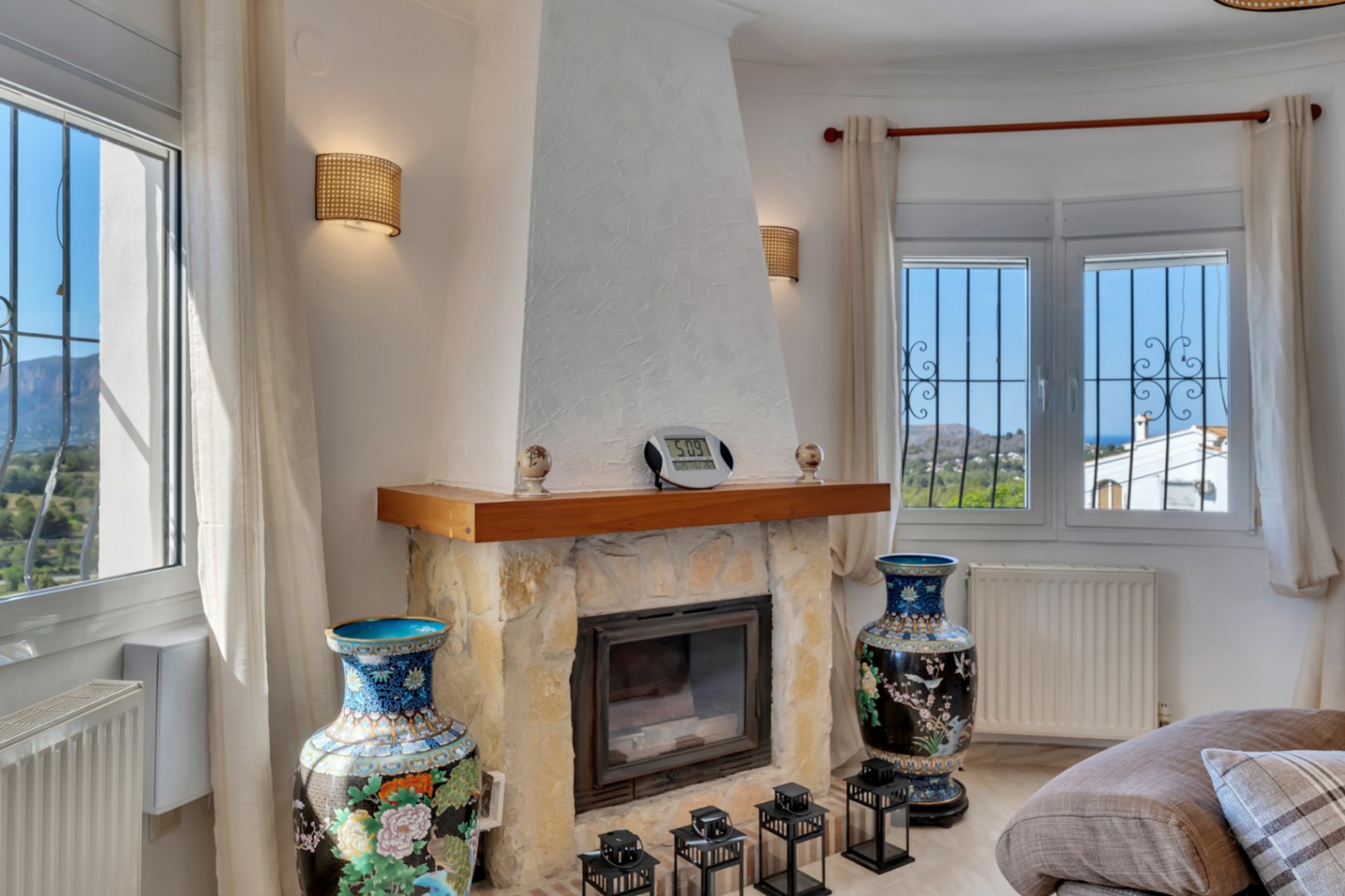 Living space featuring a stone fireplace with a wooden mantel, surrounded by windows showcasing views of the Montgó and the sea, complete with central heating.