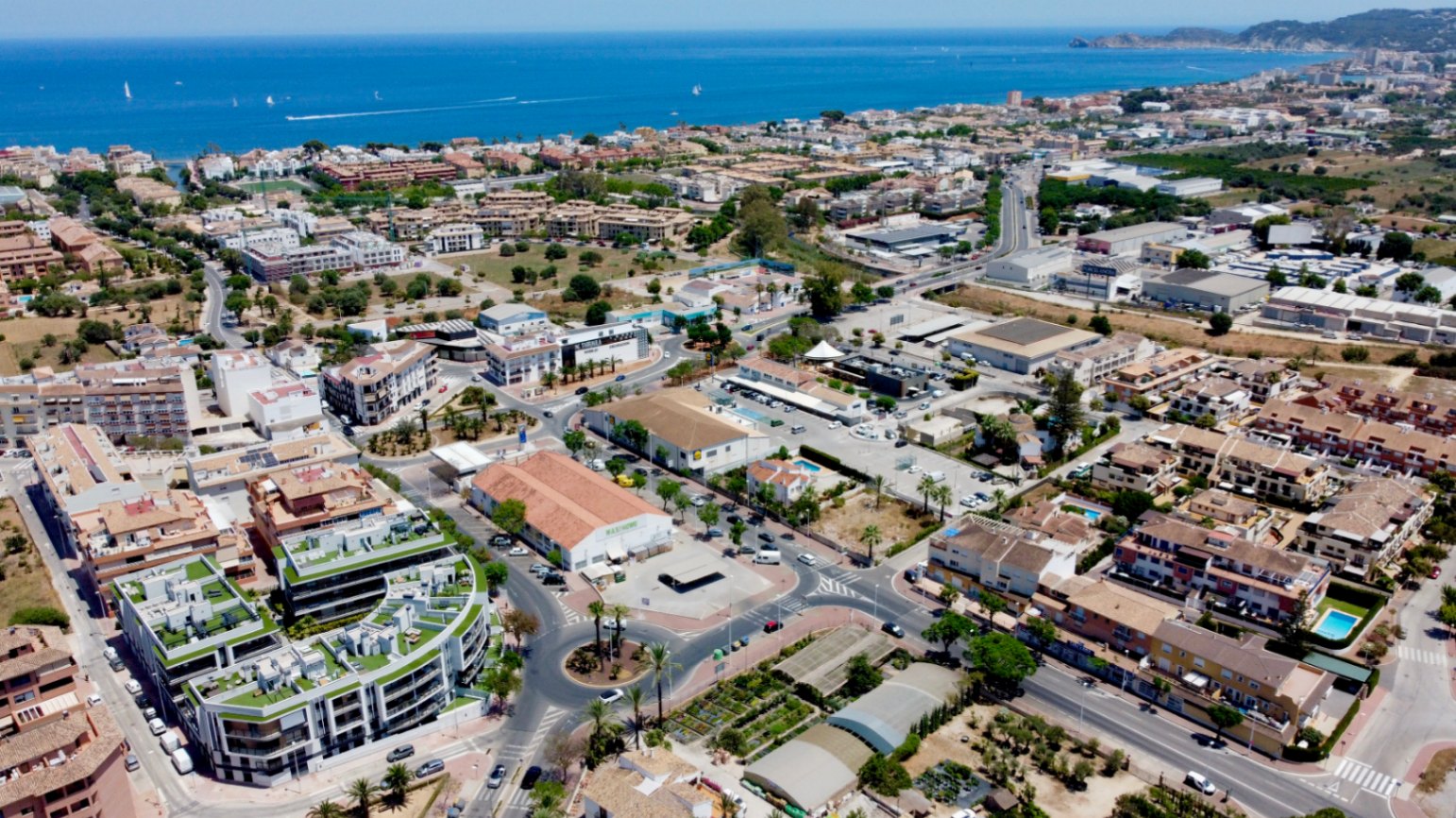 Aerial perspective of the contemporary residential building with green rooftop terraces, showing its central location between Jávea's historic center and the Mediterranean port.