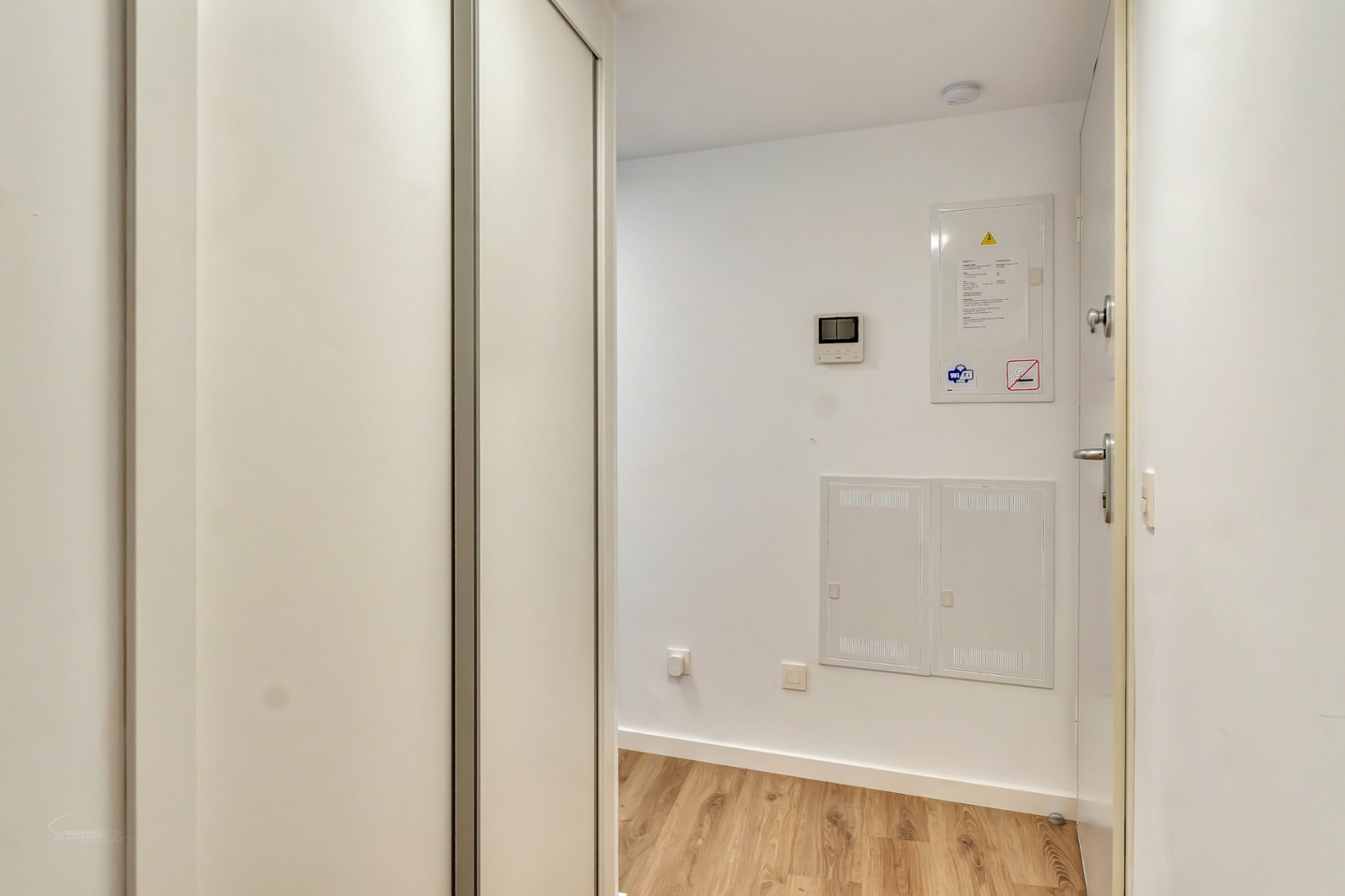 Entrance hallway featuring light wood flooring, a large white built-in closet, and integrated utility panels including a video intercom system.