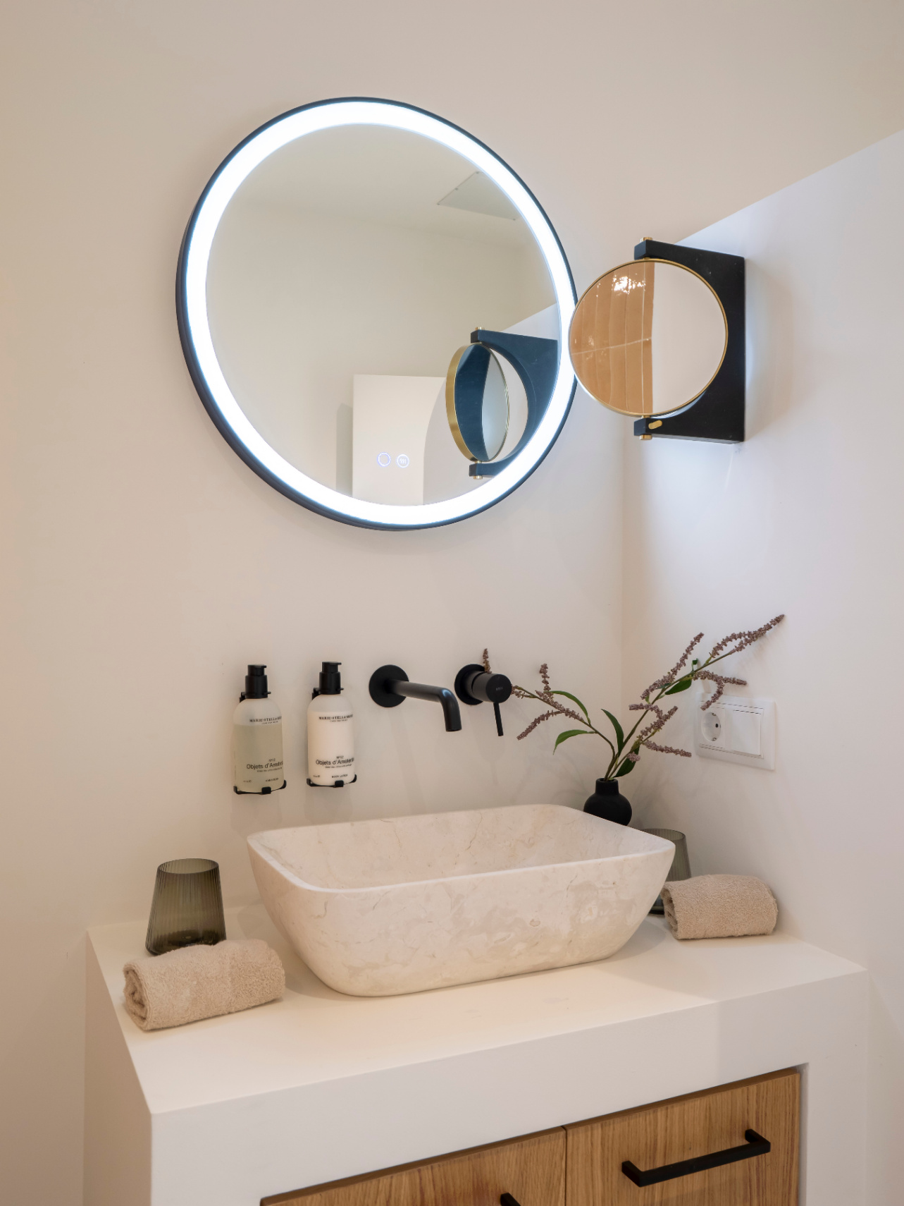 Bathroom detail with stone sink, matte black fixtures, and a LED illuminated mirror.