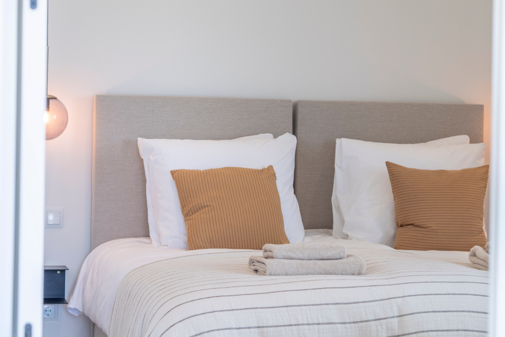 Bedroom detail with upholstered headboard, mustard pillows, and striped bedding.