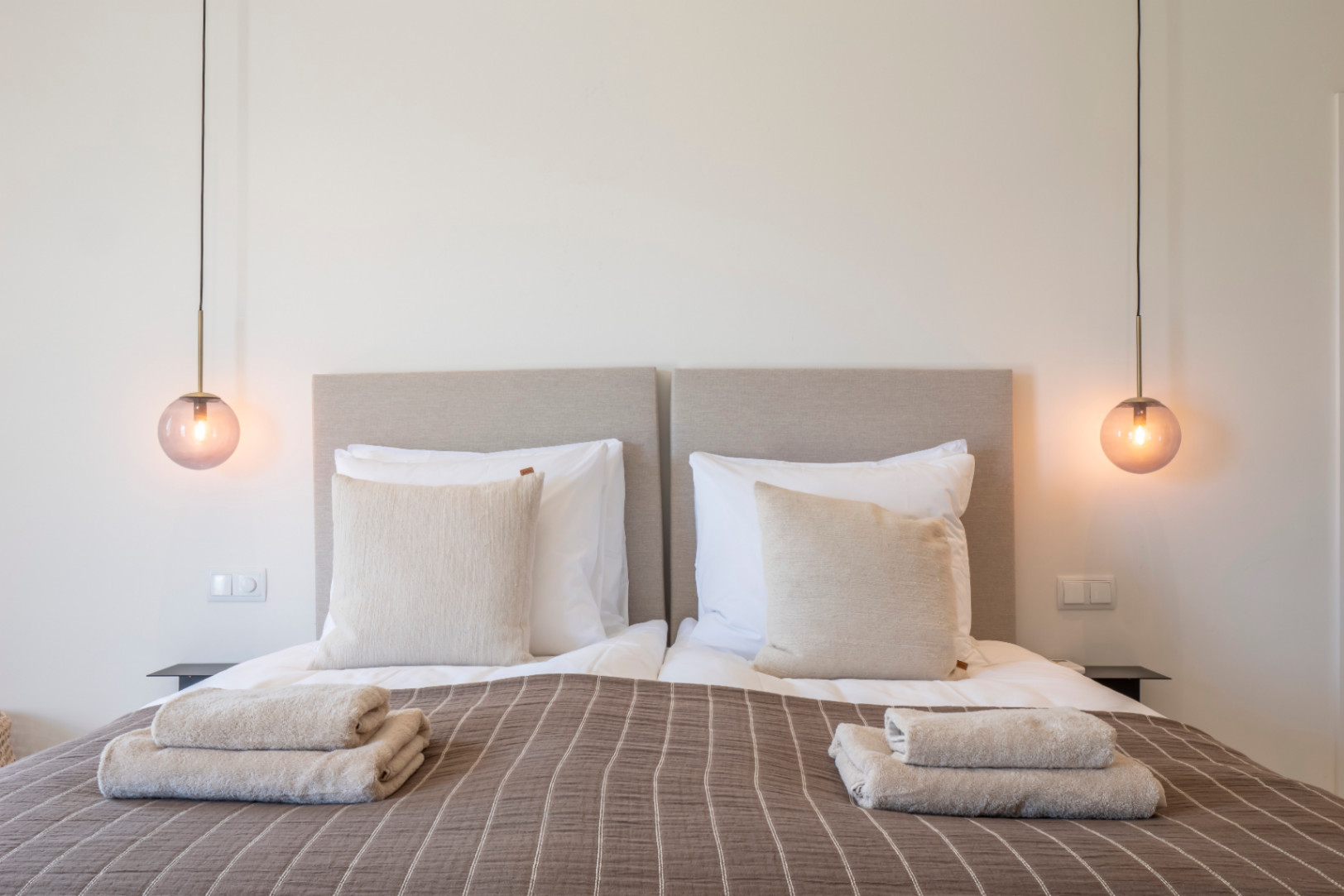 Bedroom featuring twin beds, upholstered headboards, and amber glass pendant lights.