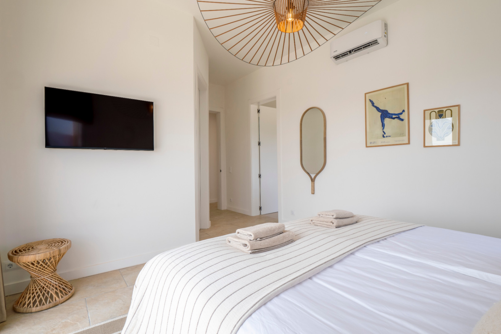 Bright bedroom featuring a TV, decorative mirror and designer ceiling lamp.