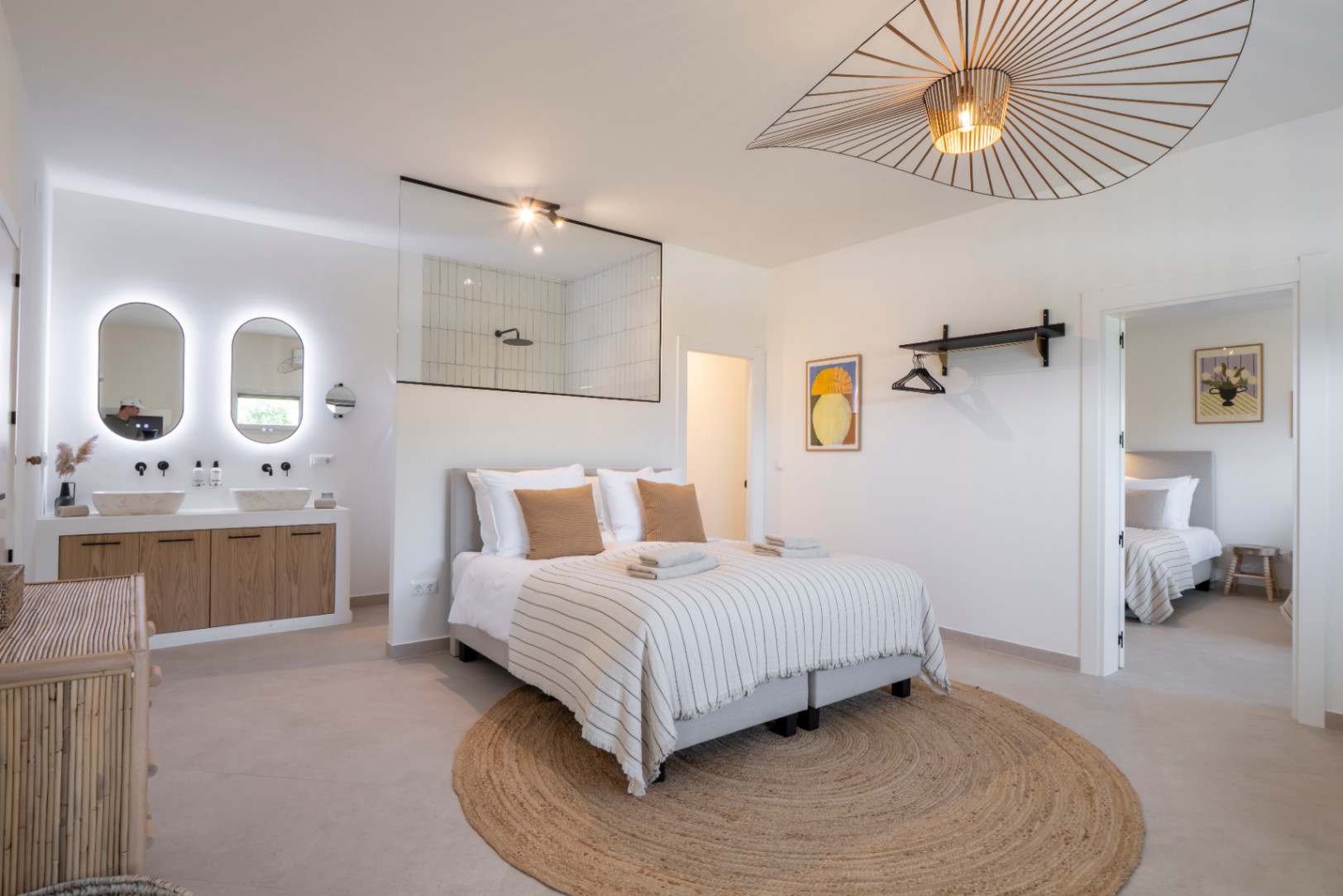 Bright bedroom featuring an integrated bathroom and double sink with backlit mirrors.