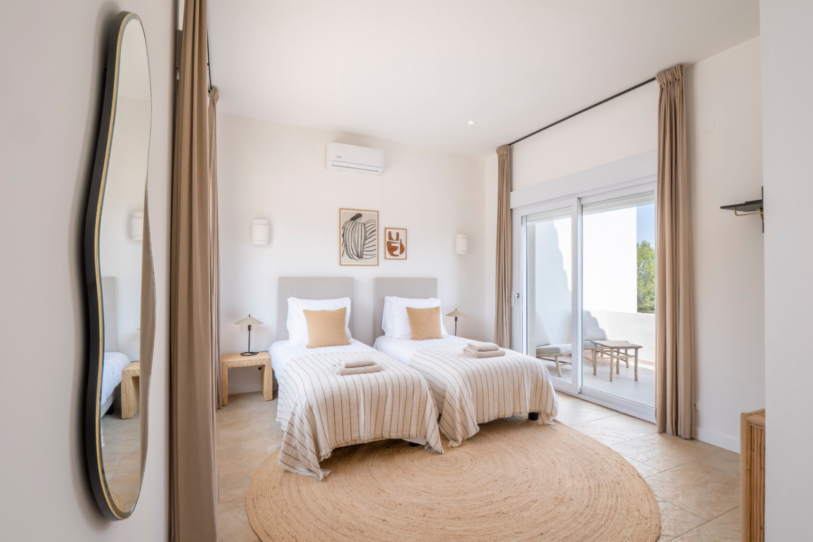 Bright bedroom featuring twin beds, a round jute rug, and access to an outdoor terrace.