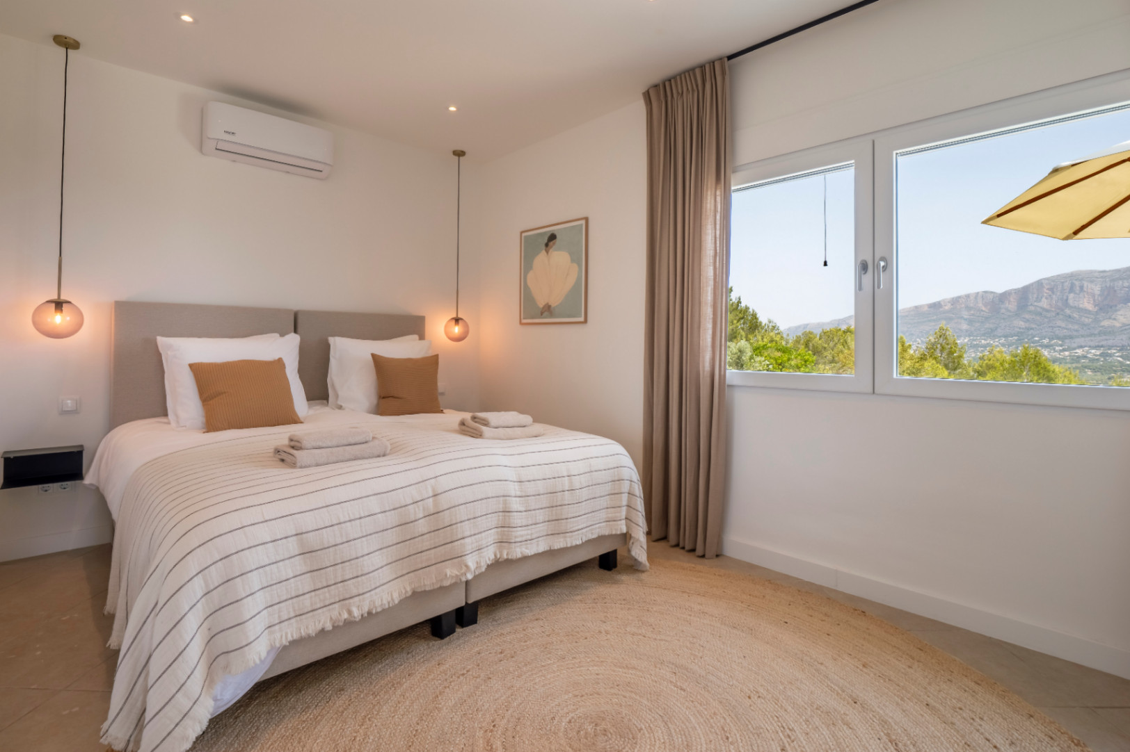 Bright bedroom with a round jute rug and mountain views.