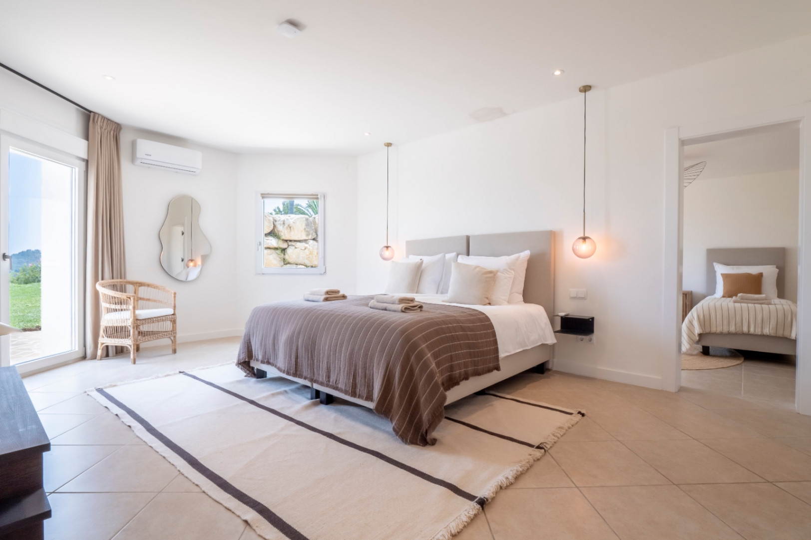 Bright bedroom with double bed, striped rug, and garden views.