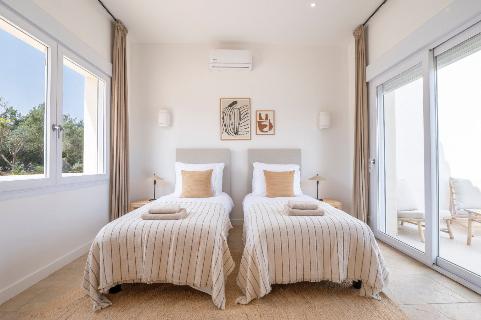 Bright bedroom with twin beds, striped linens, and minimalist decor. Access to an outdoor terrace.