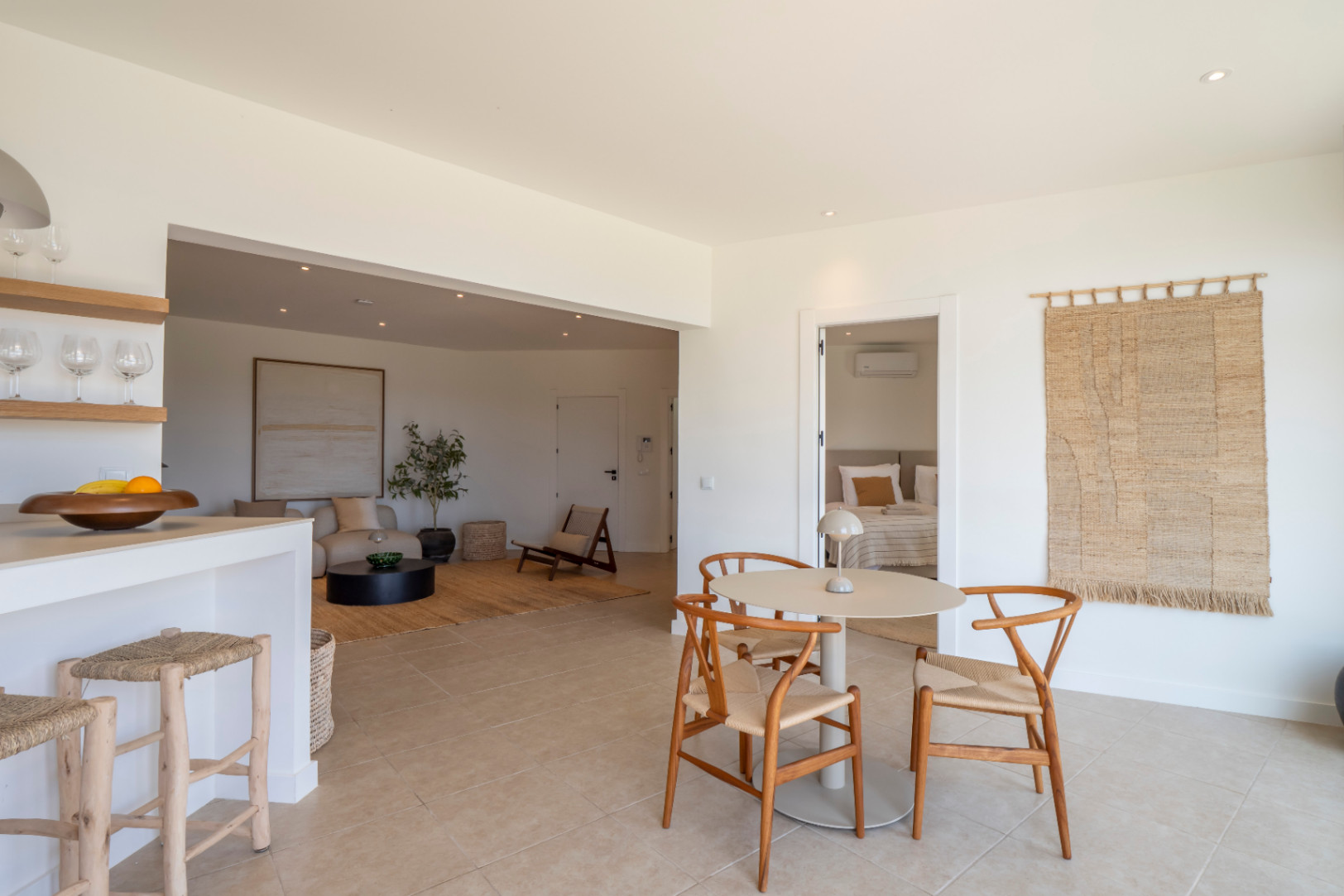 Bright interiors with a round dining table and light wood chairs, integrated into an open space with a living room and kitchen.