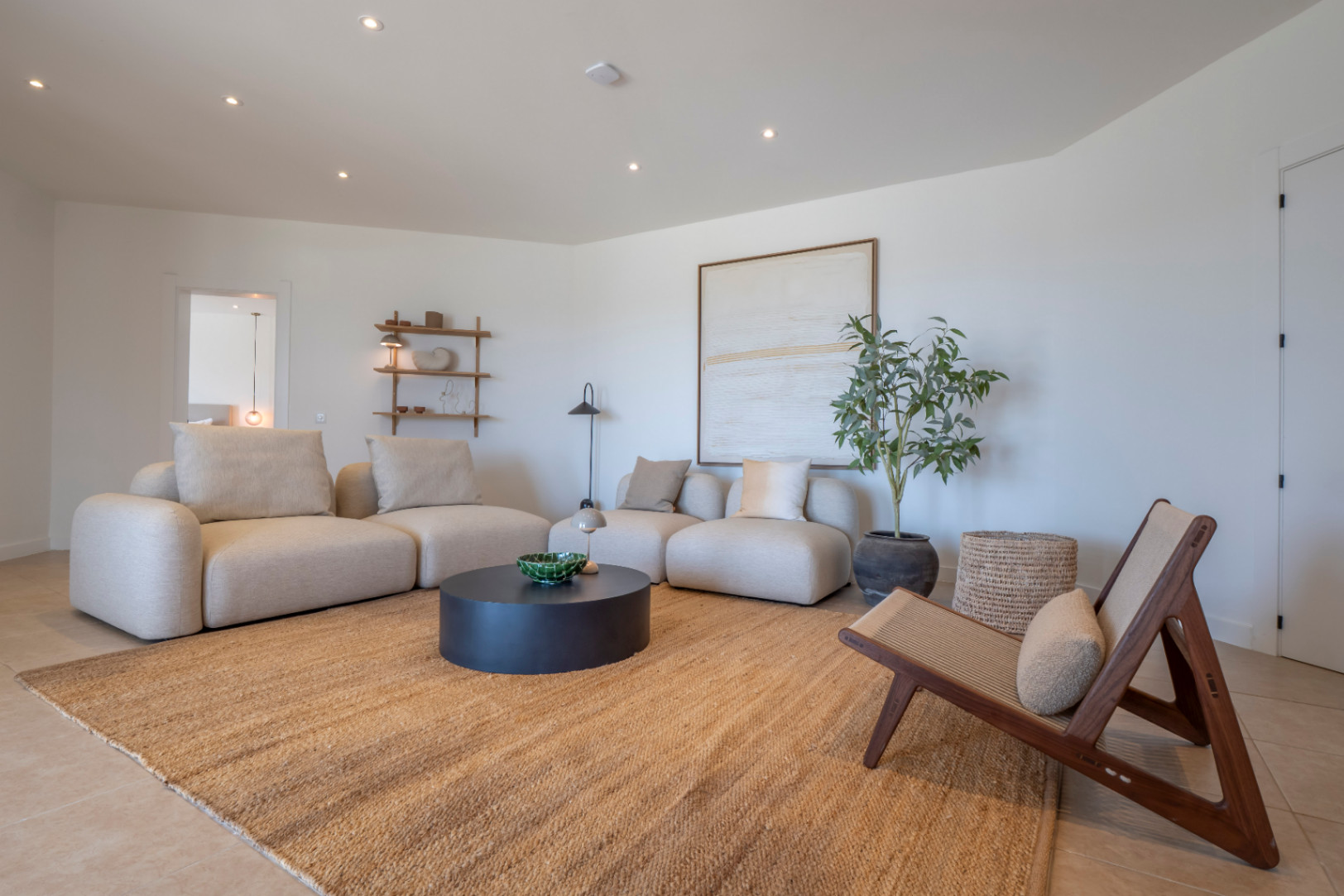Bright living room with beige modular sofas, jute rug, and minimalist decorative details.
