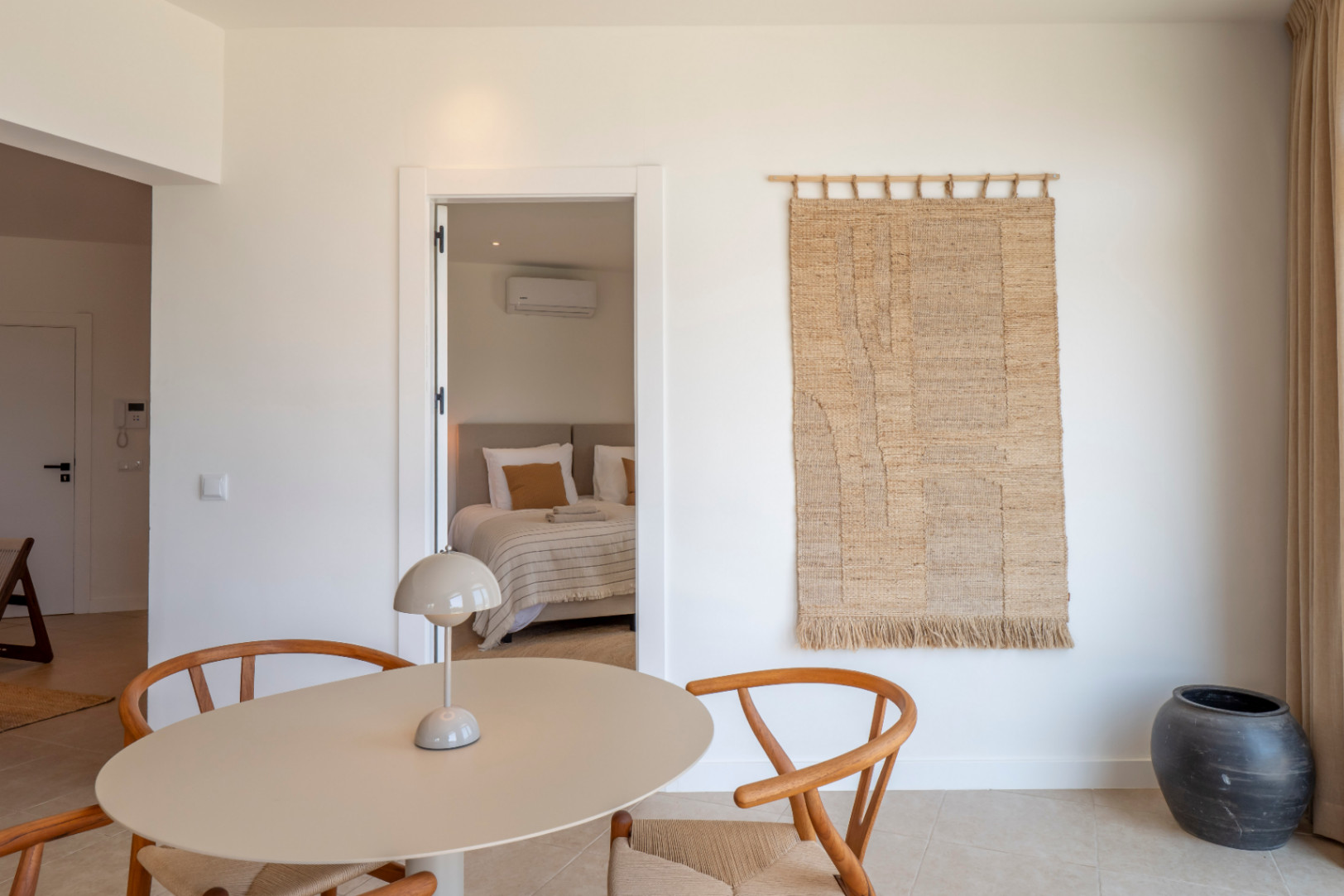 Interior detail with round table, wooden chairs, and a glimpse into the bedroom.