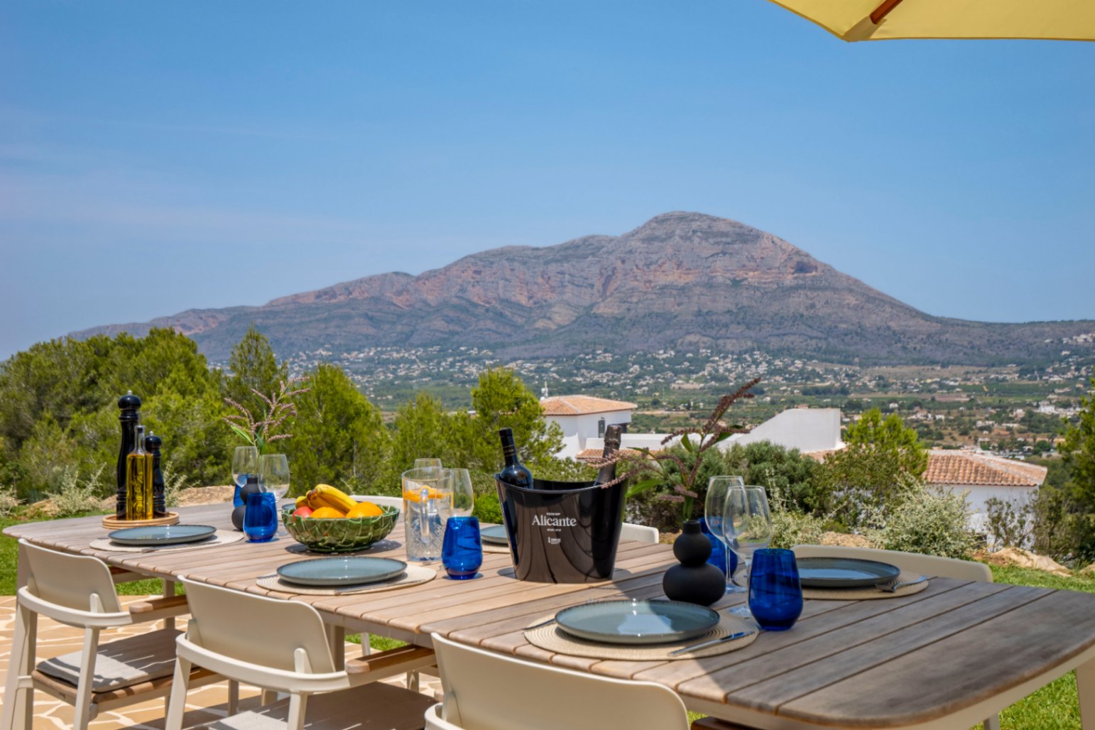 Outdoor dining area with wooden table and mountain views in Jávea.