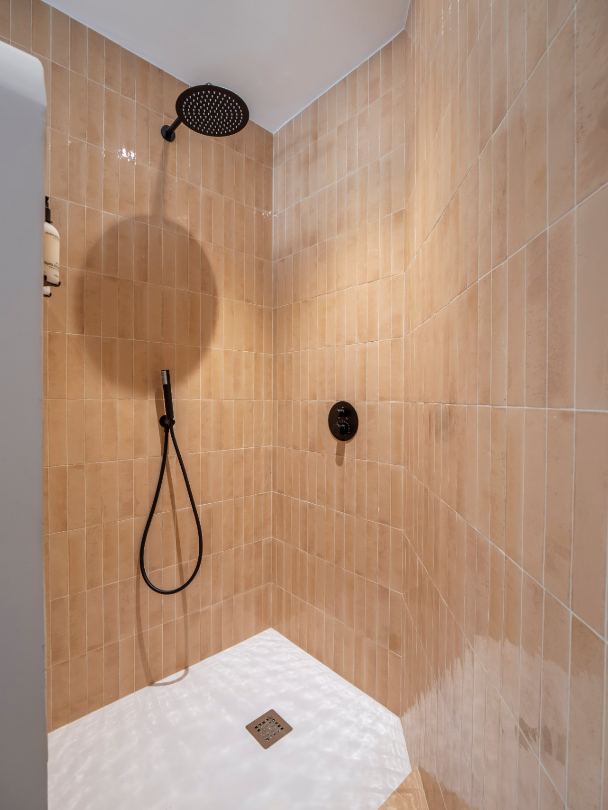 Shower detail with terracotta vertical tiles and matte black fixtures.