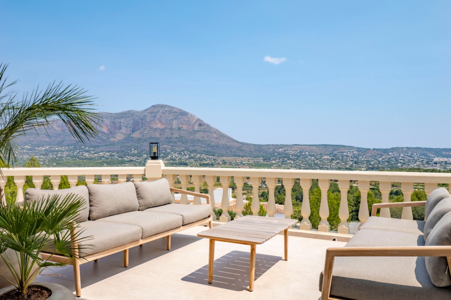 Terrace with classic balustrade, wooden outdoor furniture, and panoramic mountain views.