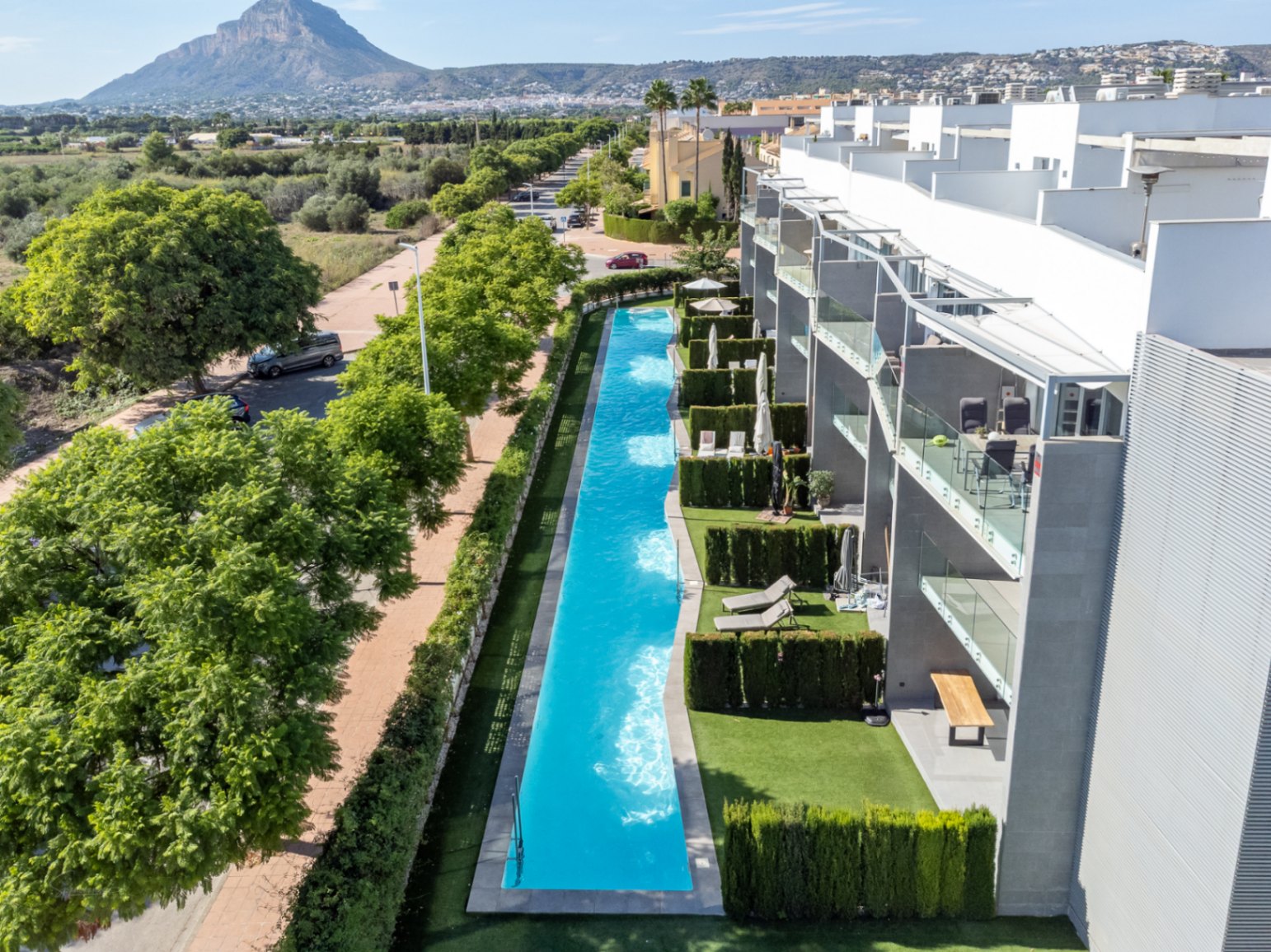 Aerial perspective of the 53-meter communal lap pool, showcasing modern architecture with glass balconies and views of the protected green landscape.