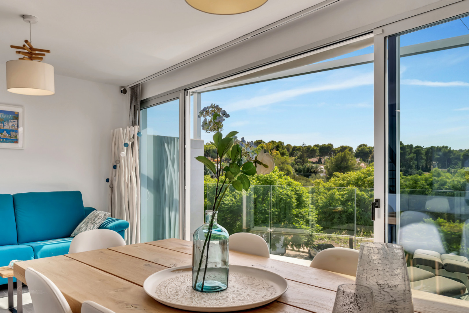 Bright dining area featuring a wooden table and large sliding glass doors that frame panoramic views of the surrounding greenery and protected fields.