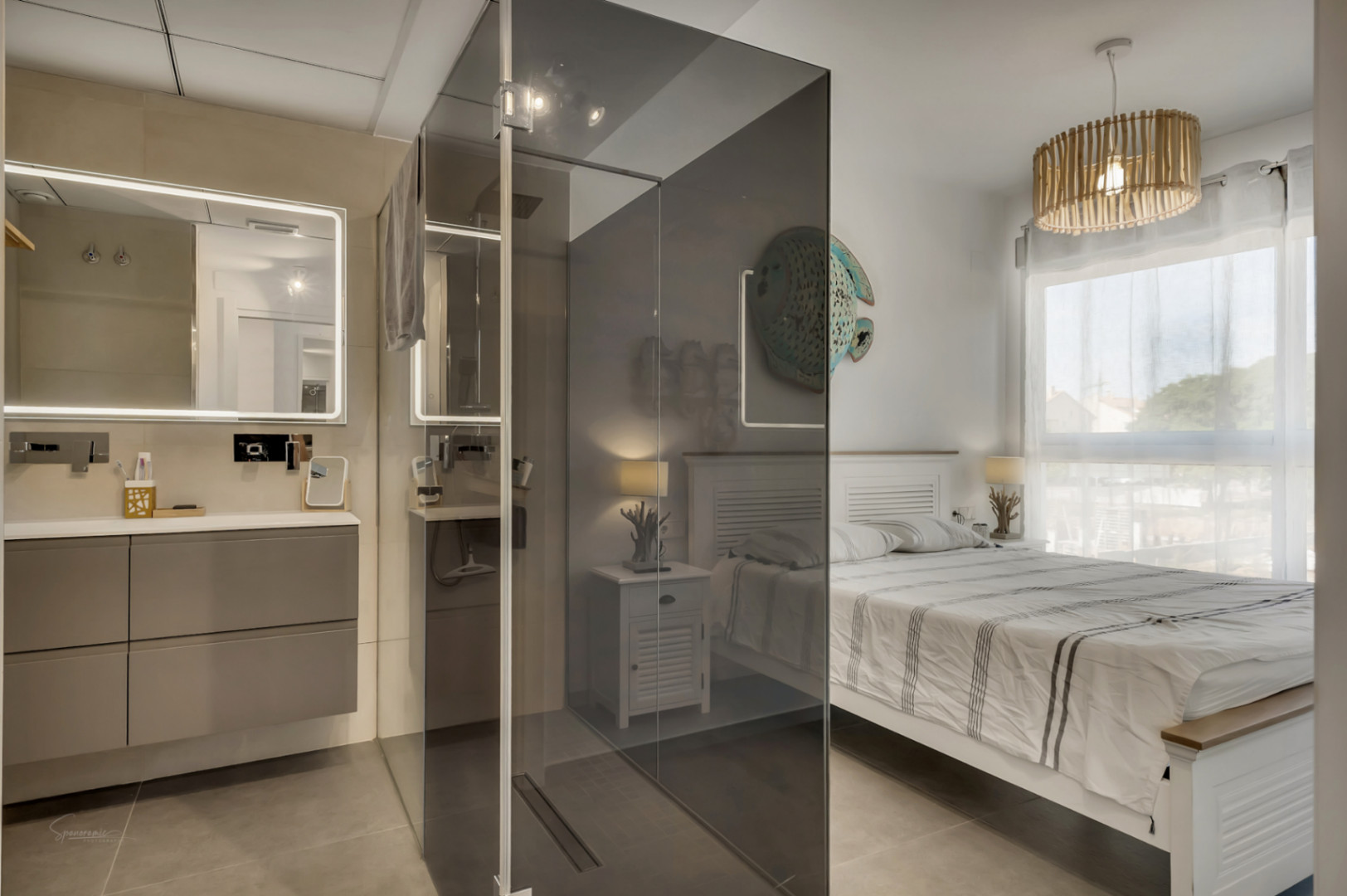 Master bedroom featuring an integrated ensuite with a smoked glass shower screen, floating vanity, backlit mirror, and a modern wooden slat pendant light.