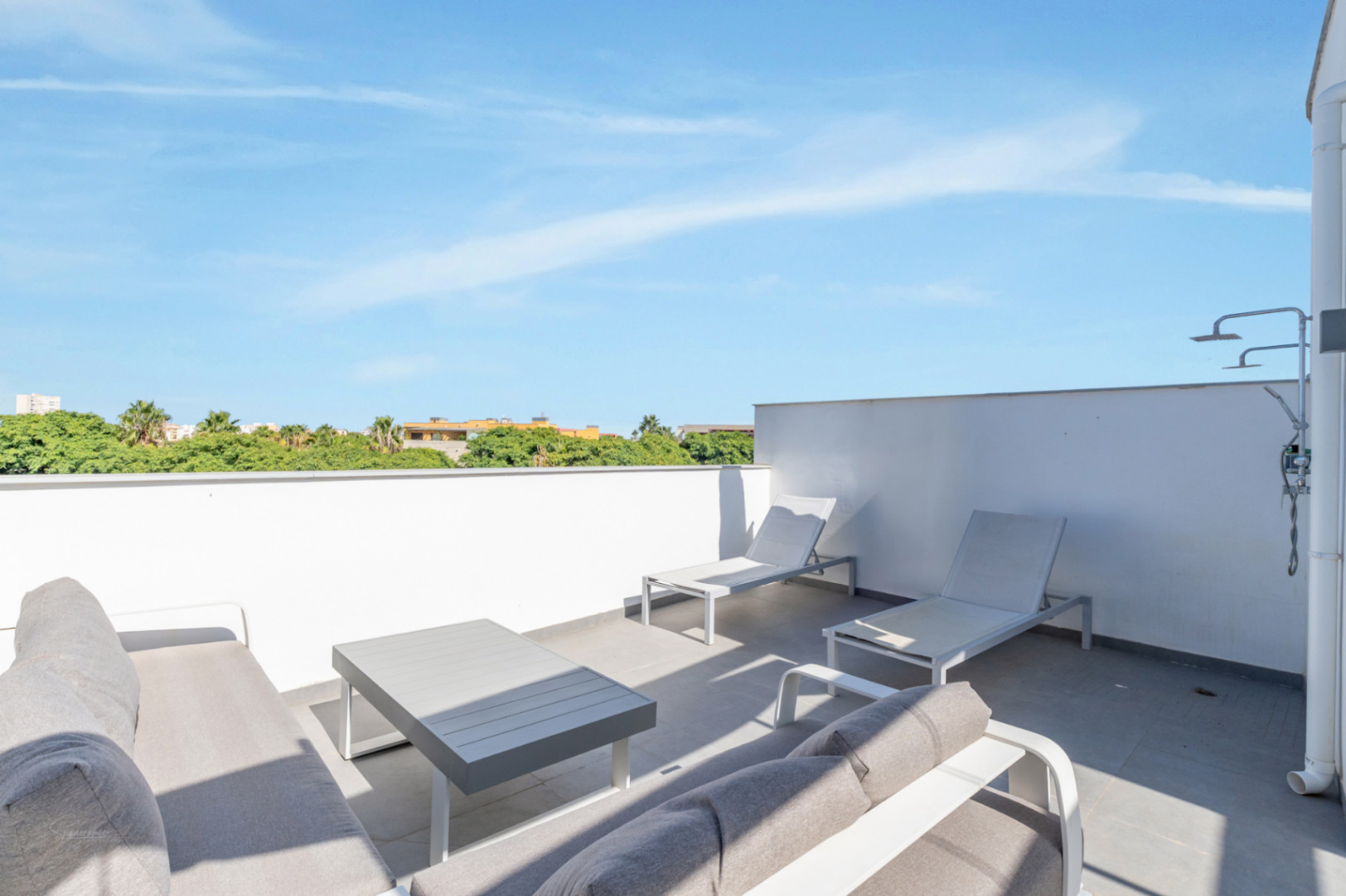 Private rooftop terrace featuring a lounge area, sun loungers, and an outdoor shower. The space offers unobstructed views of the surrounding greenery.