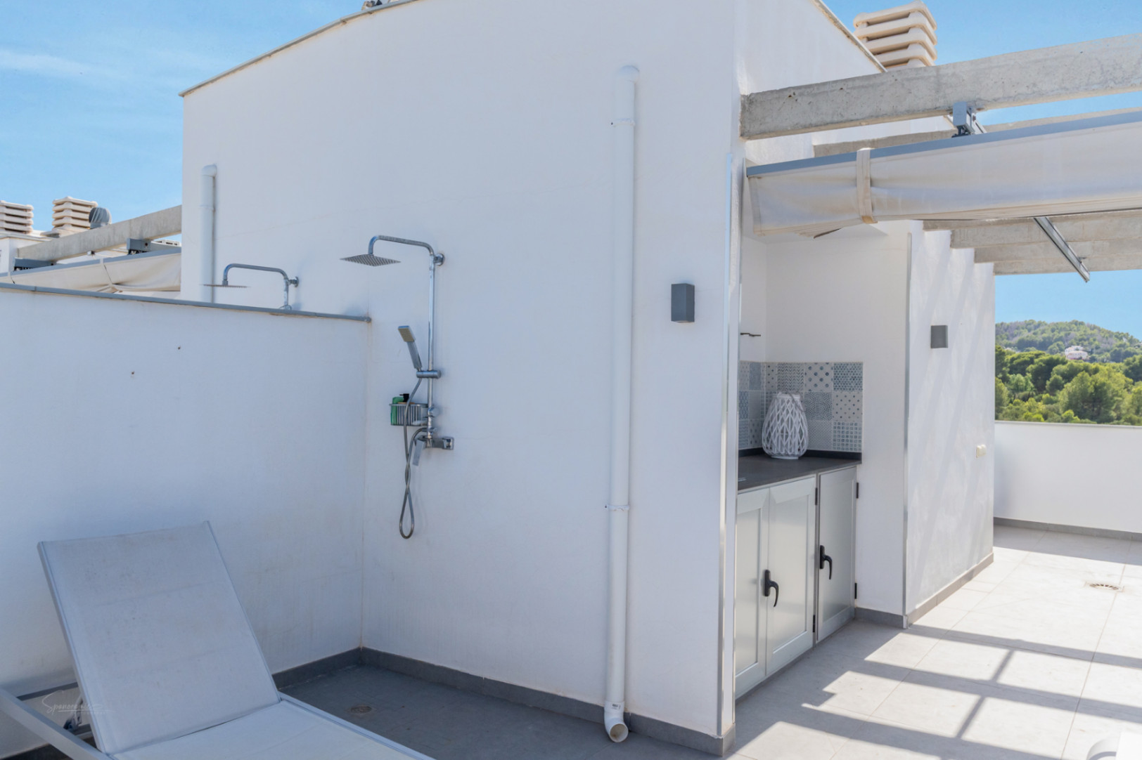Private rooftop terrace featuring an outdoor shower, a compact summer kitchen with patterned tiling, and views of the surrounding green hills.