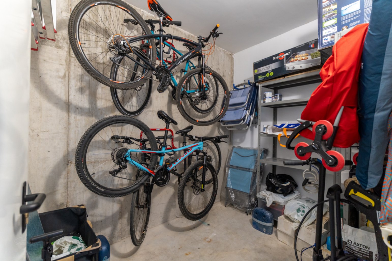 Private storage room featuring exposed concrete walls, wall-mounted bicycle racks, and metal shelving for efficient organization of sports equipment.