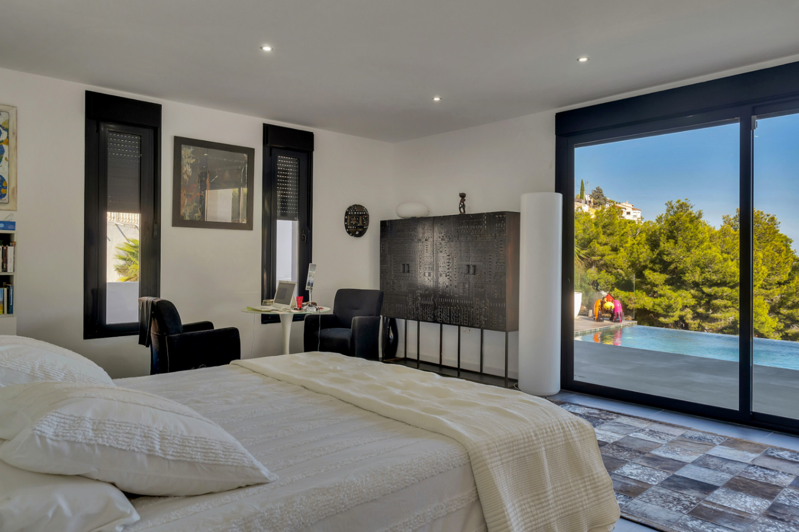 Bedroom featuring black-framed sliding doors with direct pool access, contemporary dark furniture, and recessed lighting integrated into the ceiling.