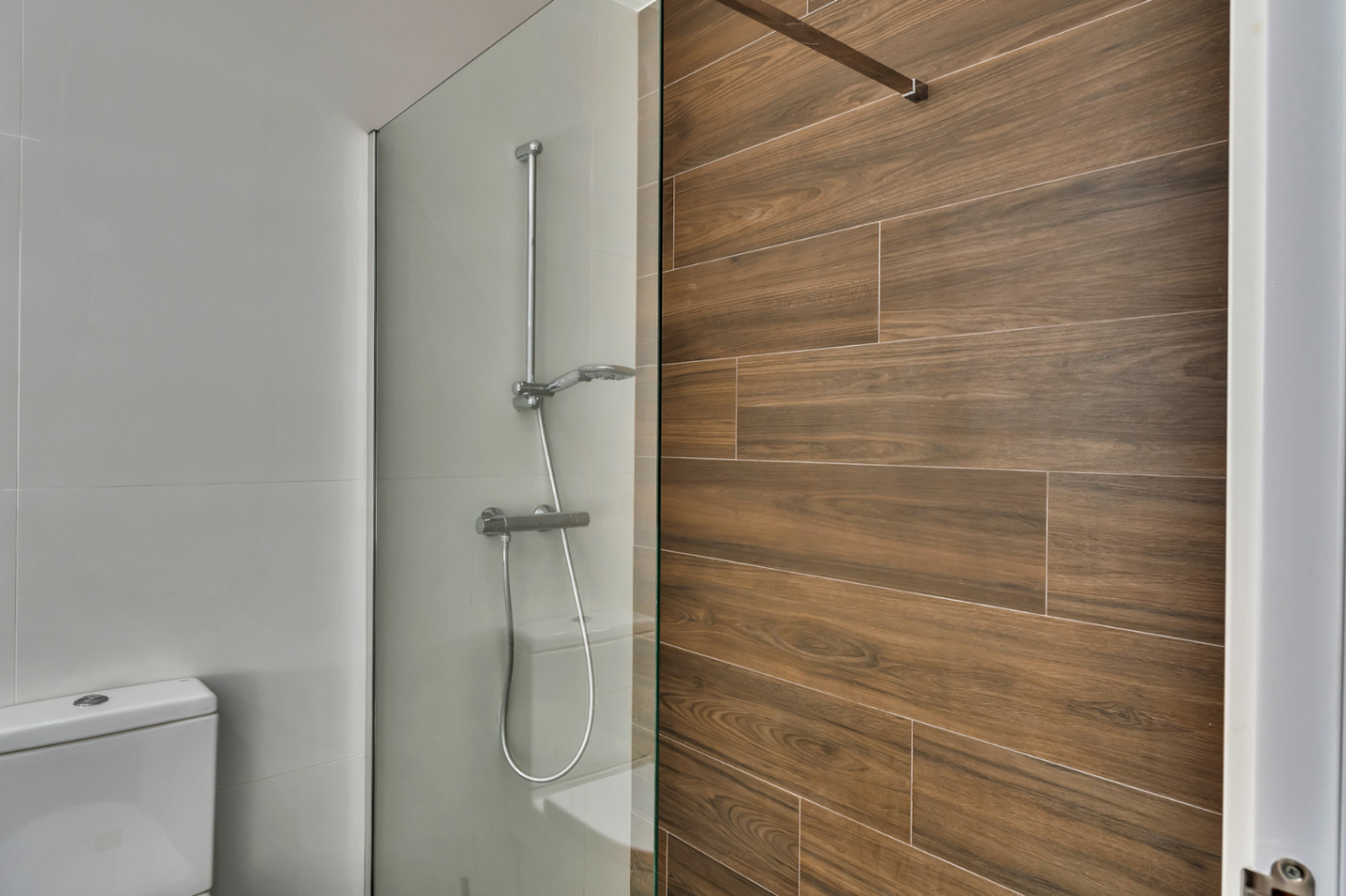 Modern bathroom featuring a walk-in shower with a glass screen and a feature wall with wood-effect ceramic tiling.