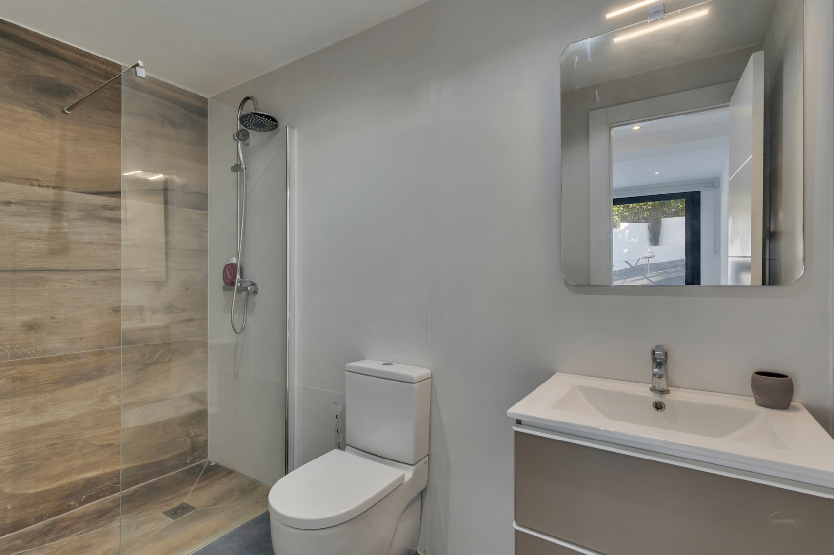 Modern bathroom featuring a walk-in shower with wood-effect porcelain tiles, a fixed glass screen, and a wall-mounted vanity with an illuminated mirror.