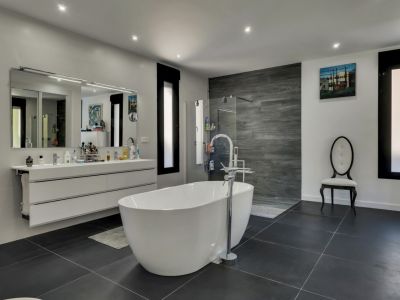 Bright bathroom featuring a freestanding white tub, floating vanity with mirror, and gray tile flooring.