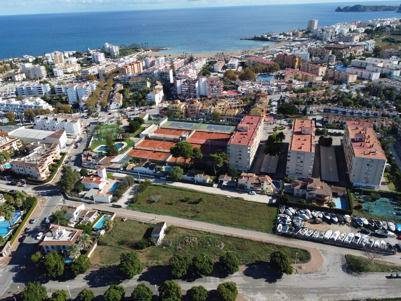 Aerial perspective of the development plot in Jávea, showing its prime location next to the tennis club and short distance to Arenal Beach and the sea.