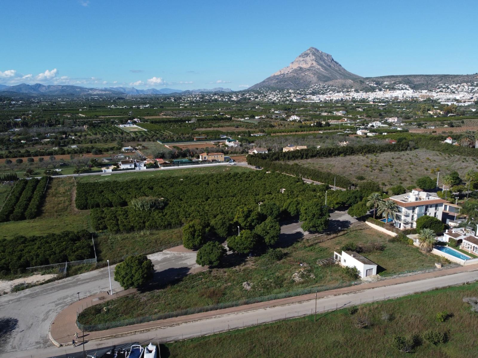 Aerial perspective of the plot showing paved access roads, neighboring citrus groves, and the iconic Montgó mountain in the background.