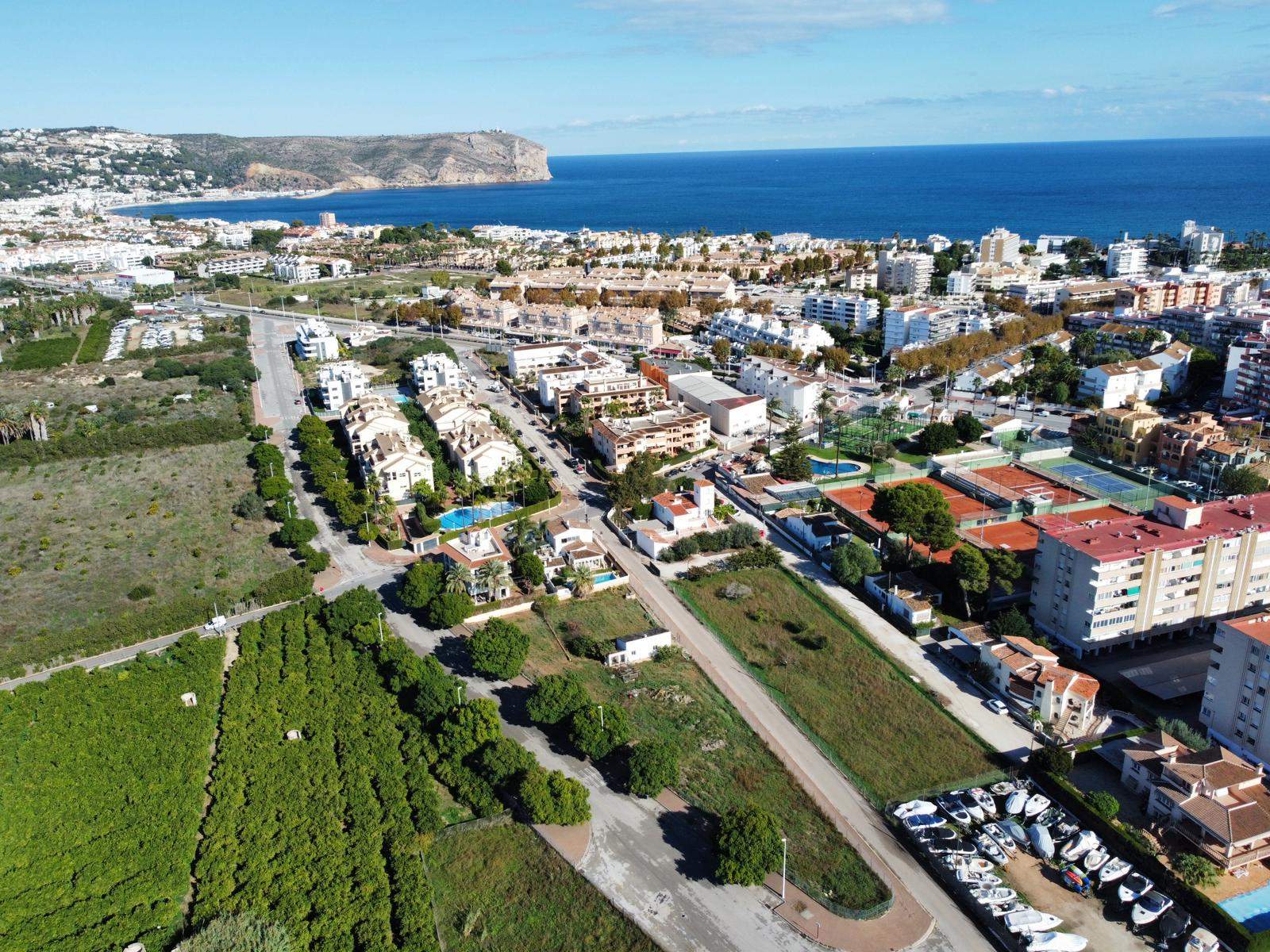 Aerial perspective of the rectangular plot bordering green fields, showing its proximity to the tennis club and the Mediterranean coastline.