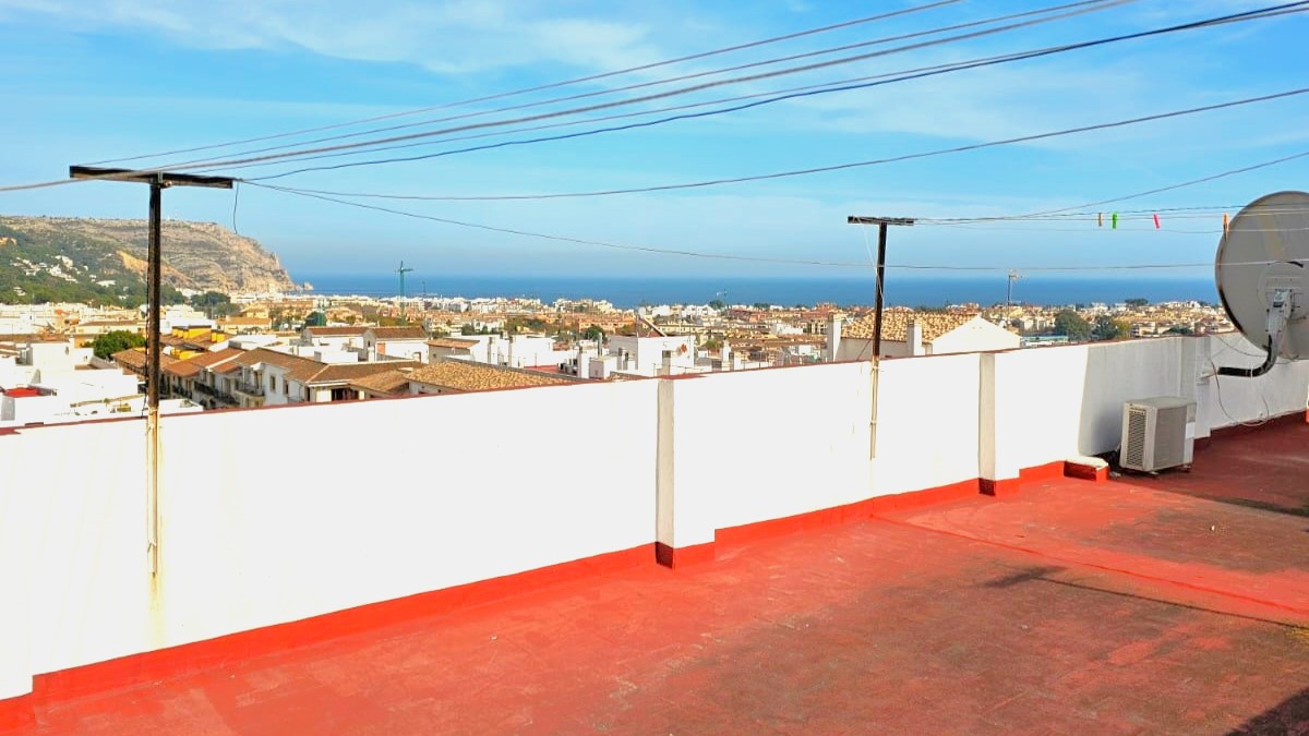 Communal roof terrace with red tiling and white walls, offering panoramic views of Javea Old Town and the Mediterranean Sea.