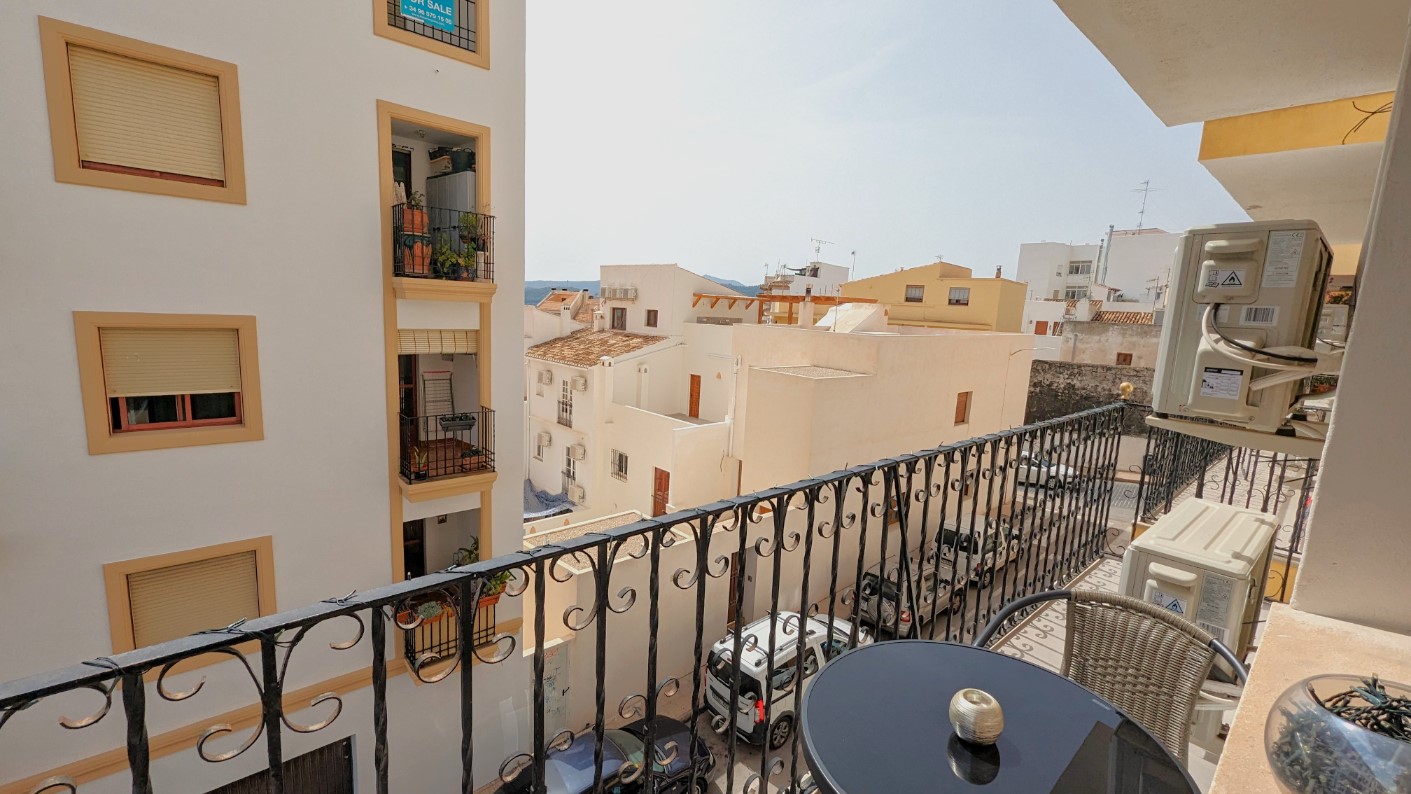 Private balcony with decorative wrought-iron railings, featuring a small bistro set and views over the traditional white-washed architecture of Javea's Old Town.