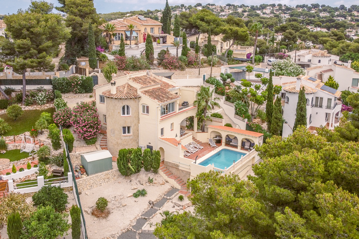 Aerial view of the south-facing villa featuring a traditional stone tower, multi-level terraces, and an 8x4m pool with a covered arched BBQ area and sun deck.