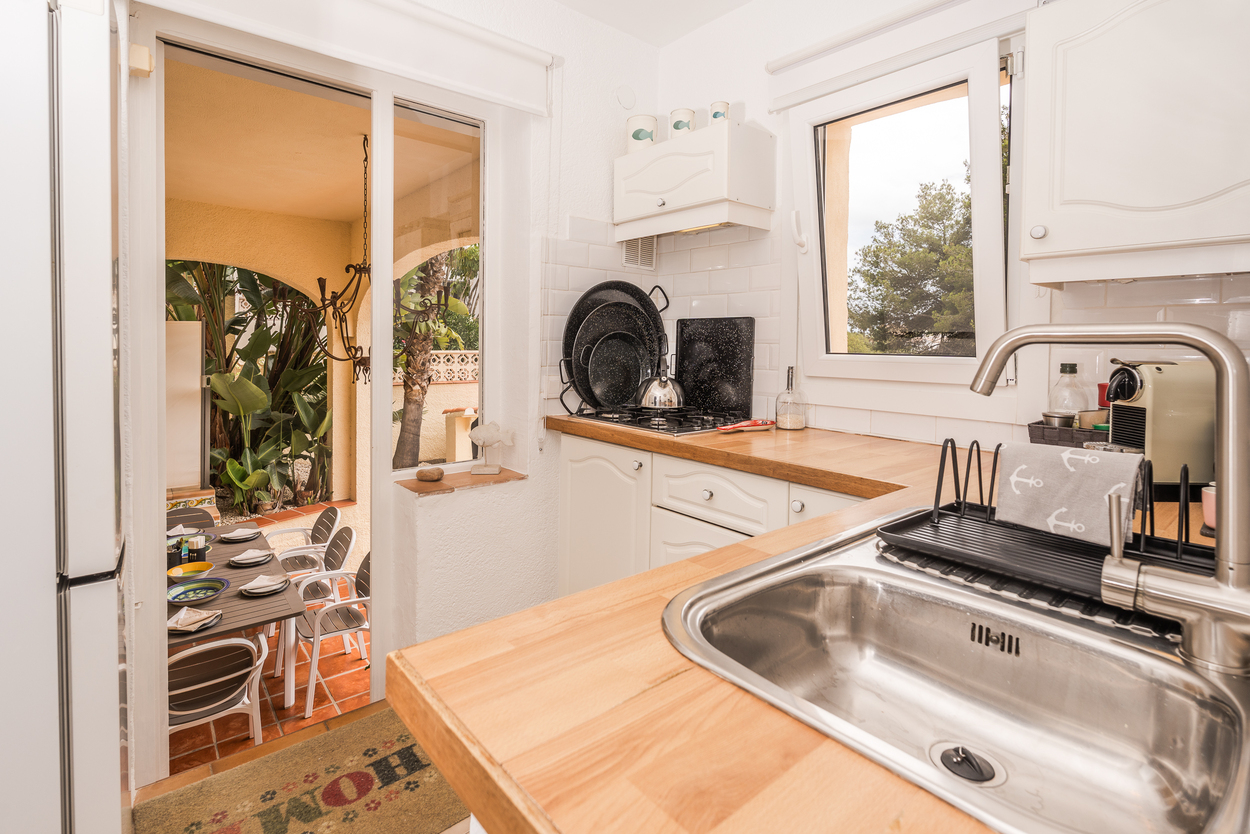 Equipped kitchen featuring solid wood countertops, subway tiling, and direct access to a covered outdoor dining area with Mediterranean arches.