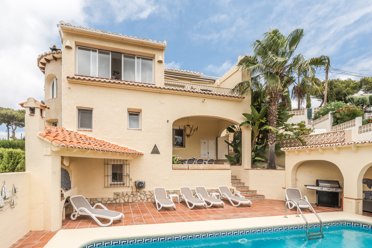 Exterior view of the south-facing villa featuring a private 8x4m pool, terracotta terrace with sun loungers, and a covered BBQ area with an arched naya.