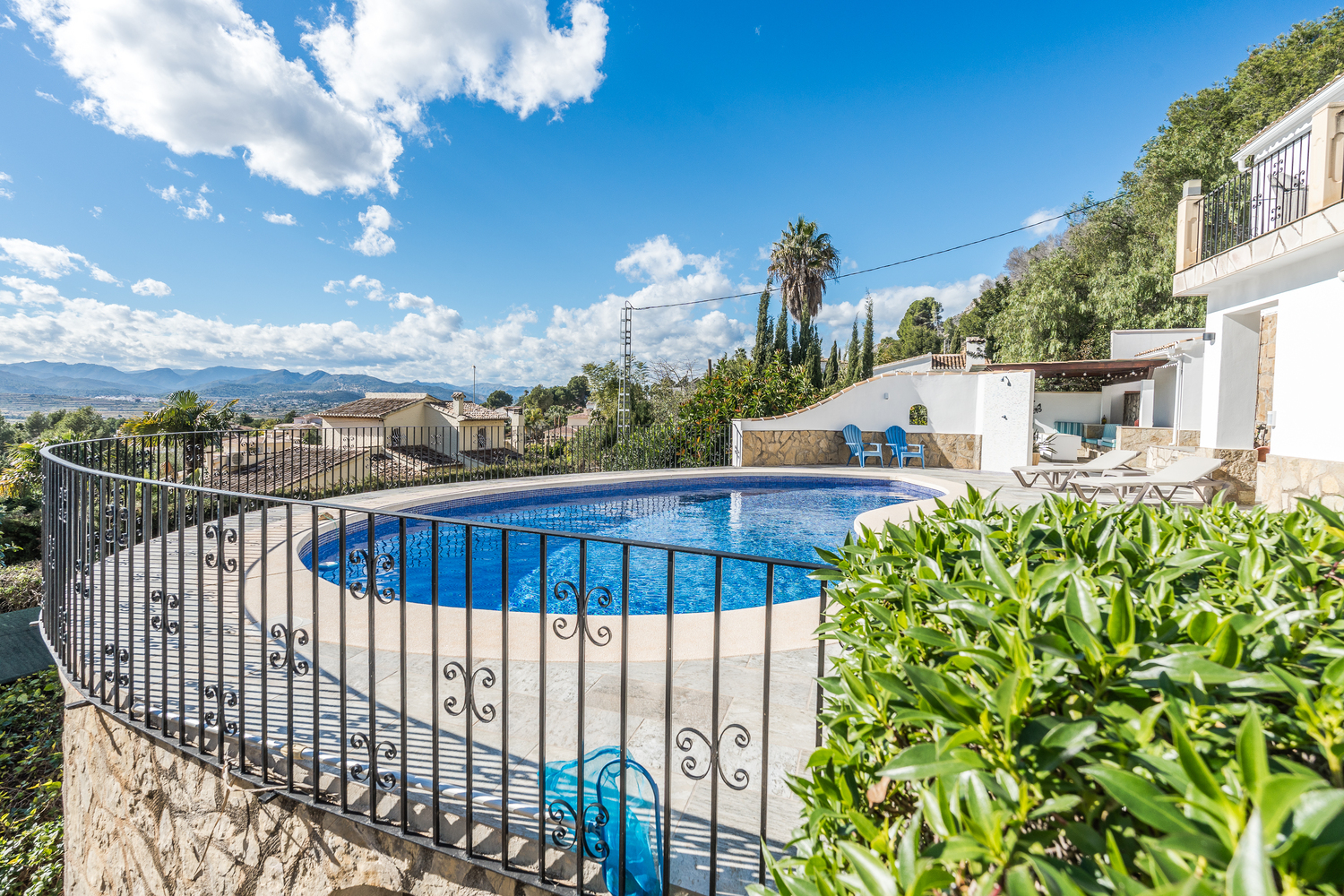 Elevated terrace featuring a kidney-shaped swimming pool, decorative iron railings, and panoramic valley views under a clear sky.