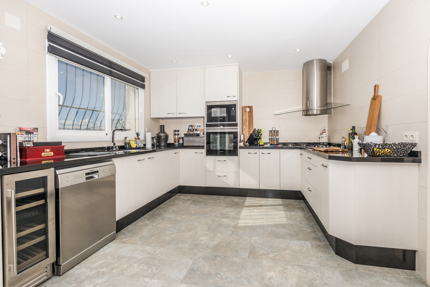 Modern kitchen featuring white cabinetry, black stone countertops, and high-end stainless steel appliances including a wine cooler and integrated Siemens oven.